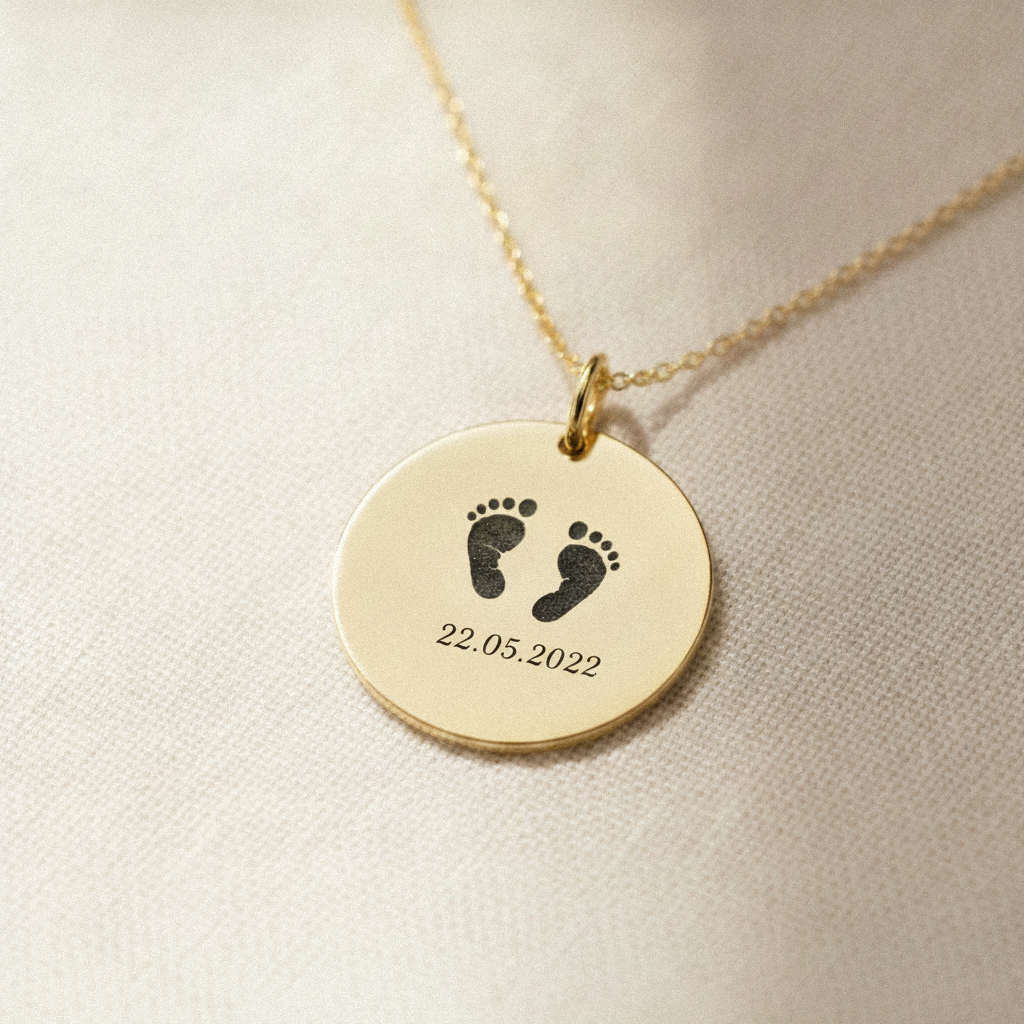 Macro of gold footprint pendant with printed date