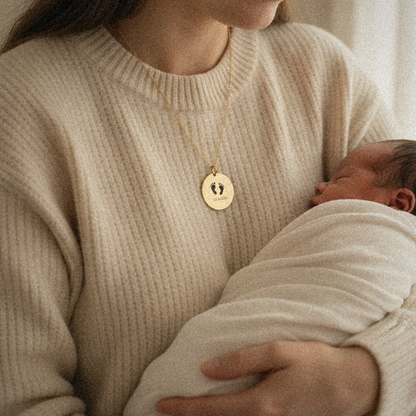 Mother wearing the footprint pendant holding her swaddled newborn