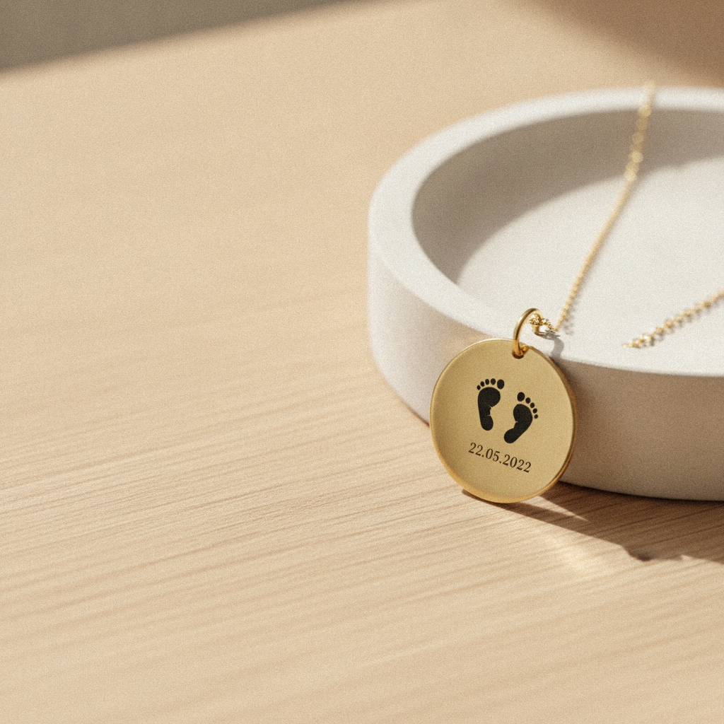 Gold baby footprint pendant necklace on a ring dish